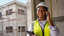 Engineer on a construction site using a phone and holding a tablet