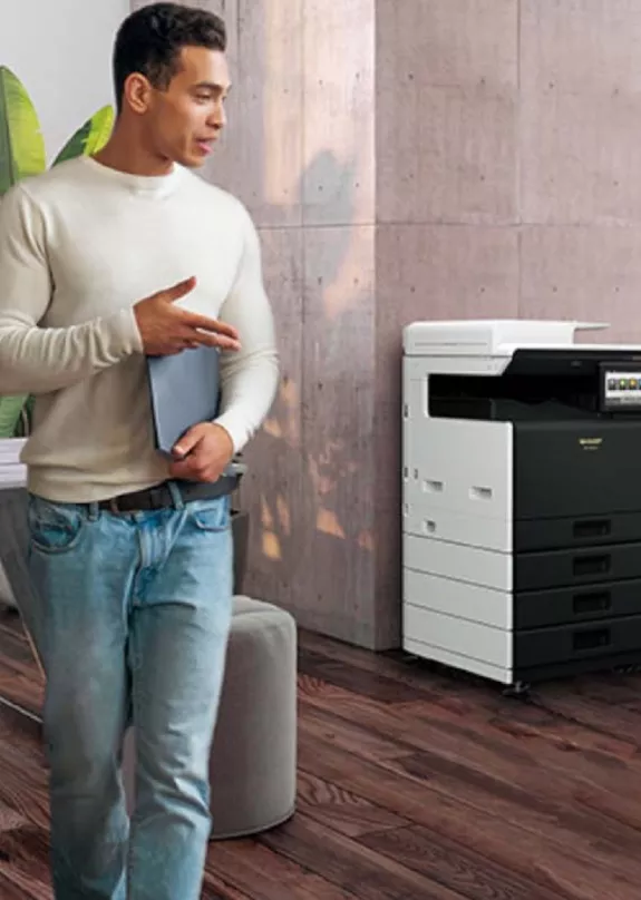 A man in an office next to an MFP